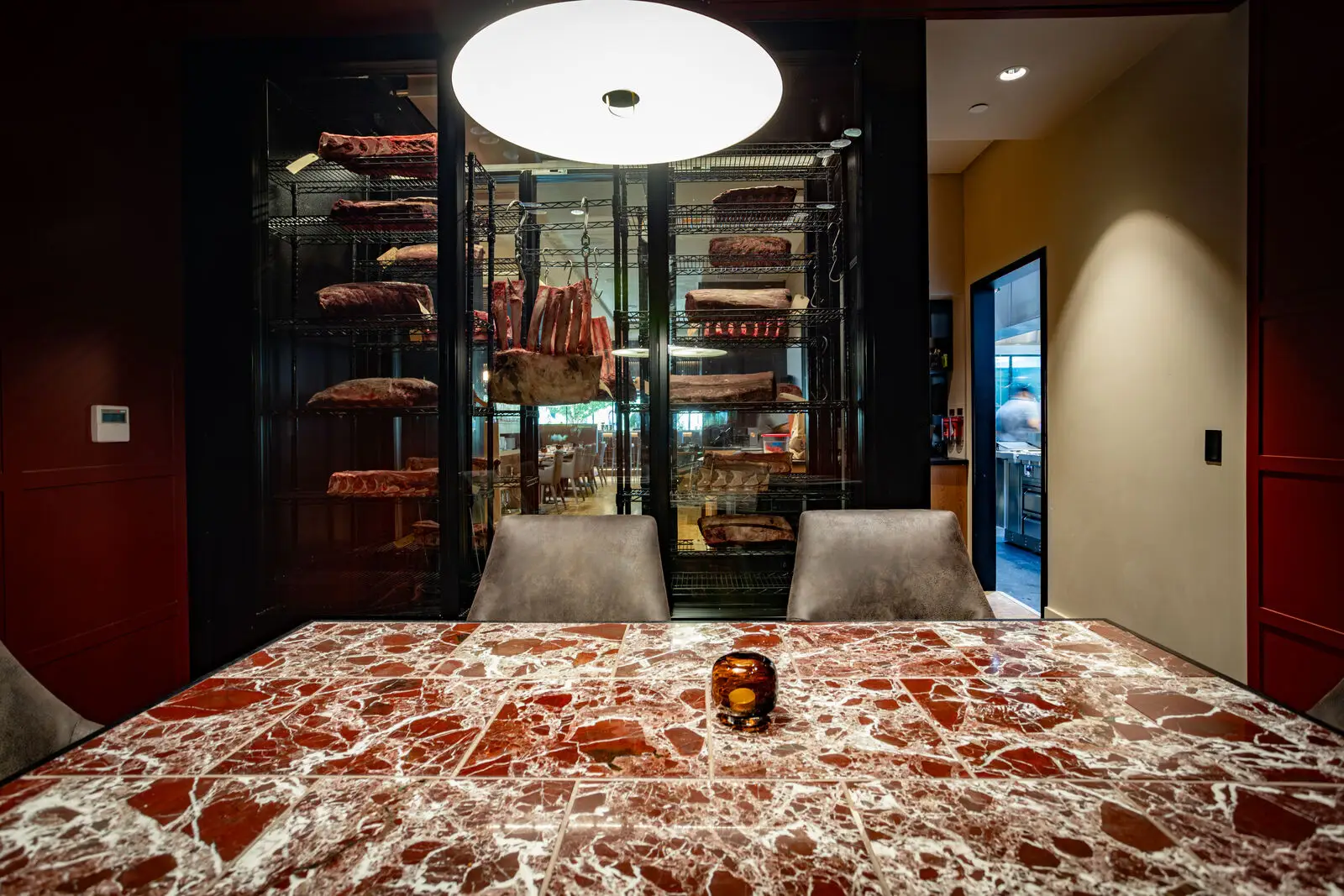 Intimate view of the Gangster Room private dining table at Crawford Brothers with dry-aged steaks visible behind glass
